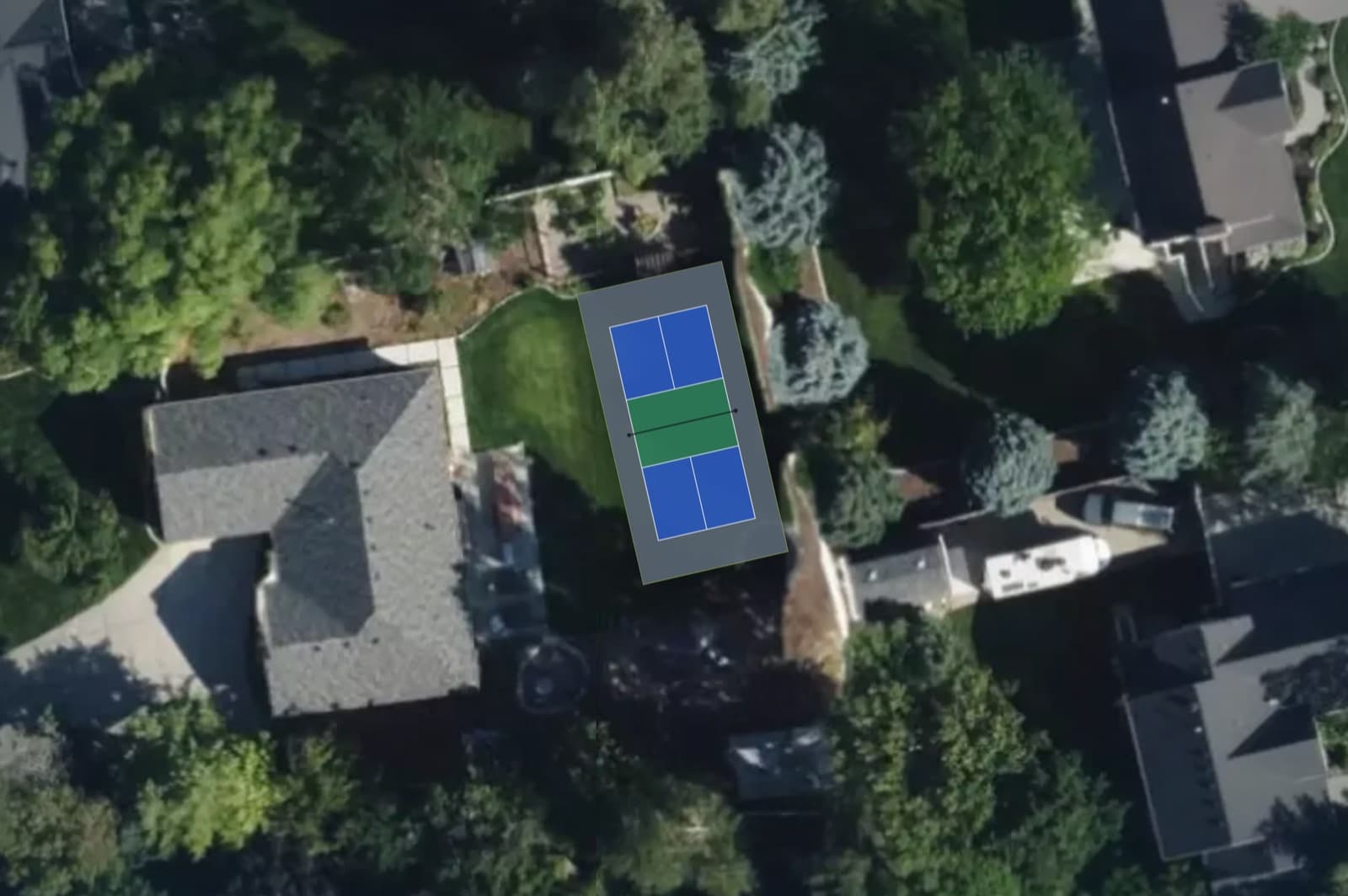 Satellite view of a backyard with a pickleball court plan positioned over the lawn.